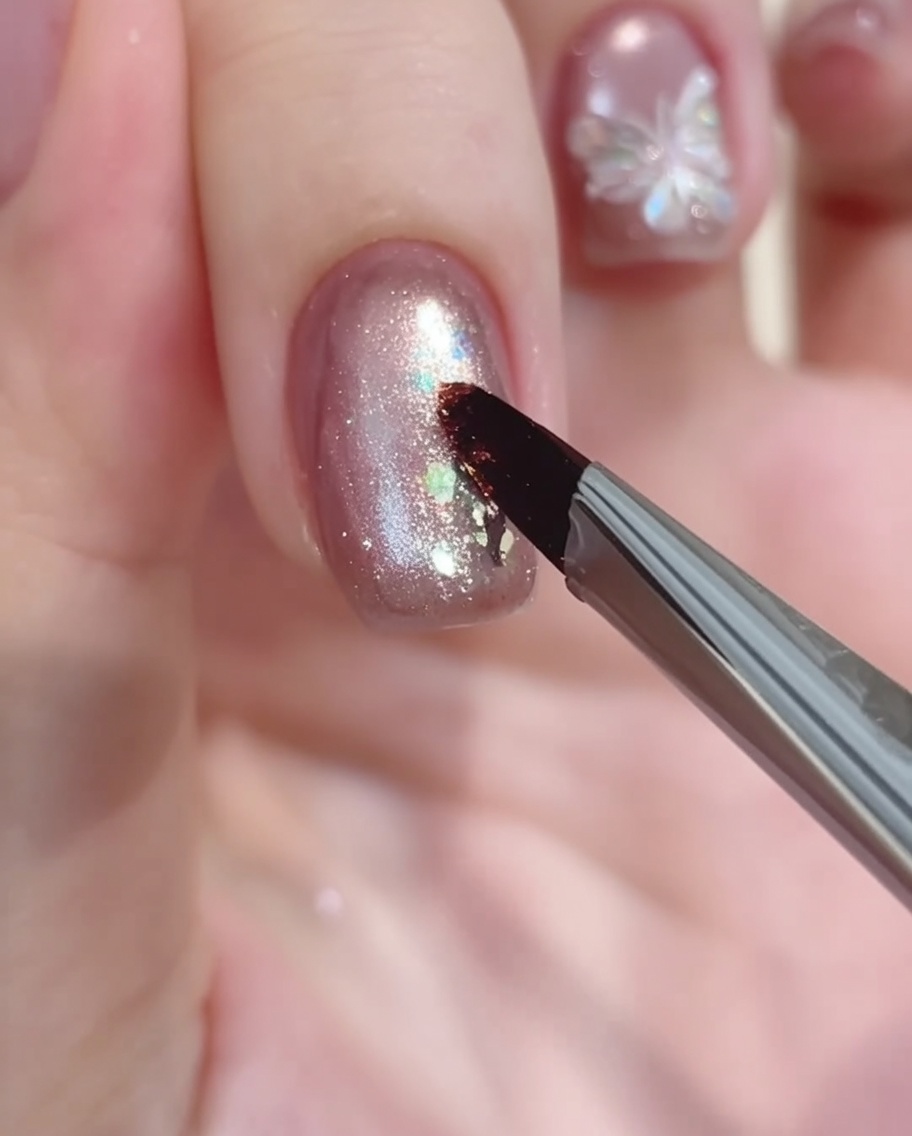 Ein Nailart-Pinsel setzt einen kleinen Punkt weißes Gel als Ausgangspunkt für ein Blumendesign.
