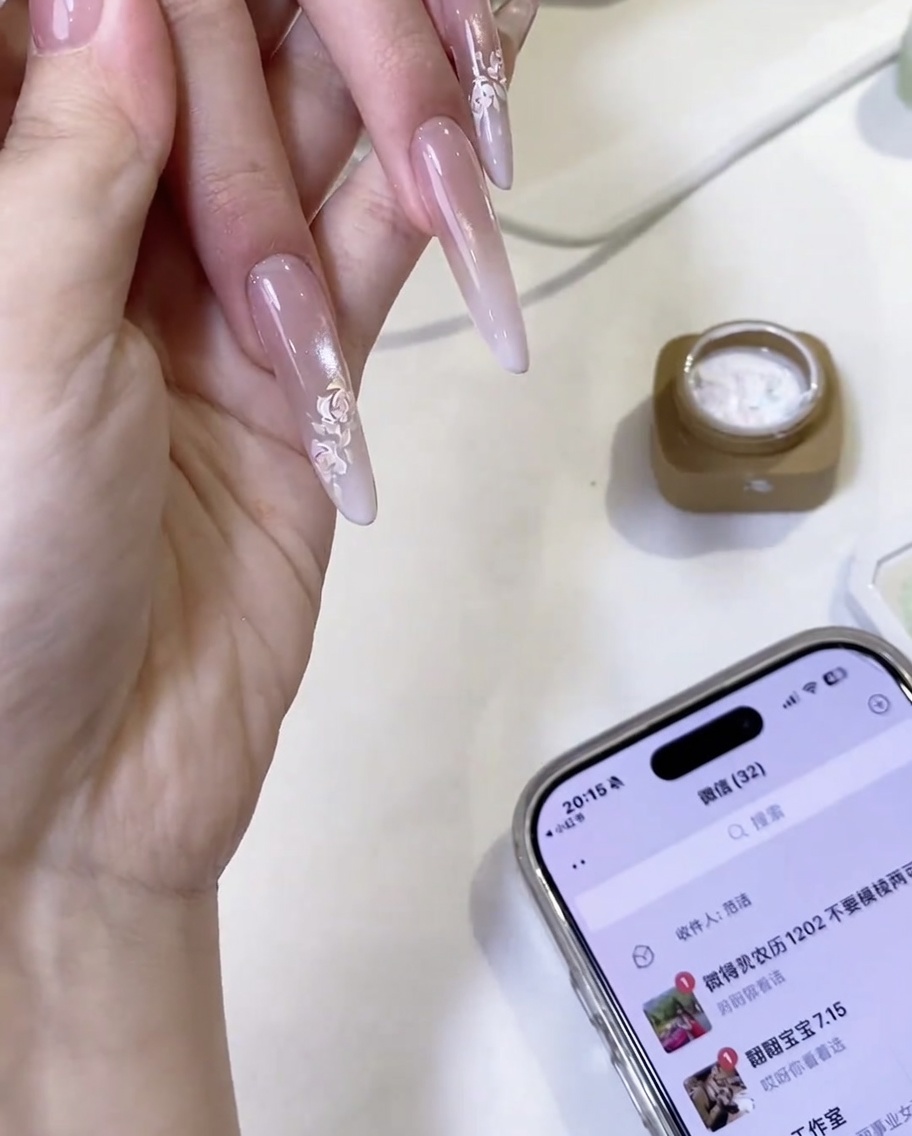Ein fertig handgemaltes weißes Rosendesign auf einem Nagel mit überlappenden Blattdetails.