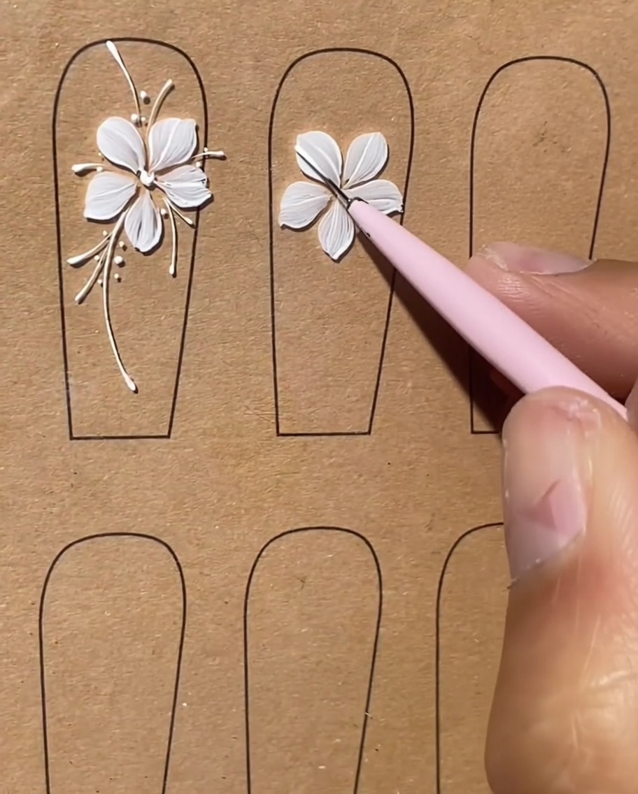 Ein Nagel mit weißem Blumendesign und langen, dünnen weißen Linien, die wie Stiele nach außen ragen.