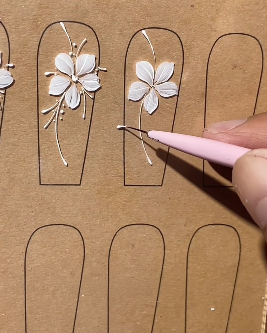 Nahaufnahme eines Liner-Pinsels, der lange, zarte weiße Linien zwischen den Blütenblättern einer gemalten Blume hinzufügt.