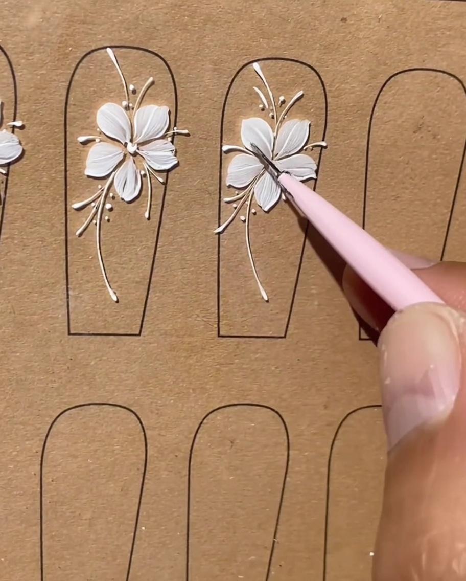 Eine finale Nahaufnahme eines vollendeten weißen Blumen-Nageldesigns mit sauberen und verfeinerten Linien.