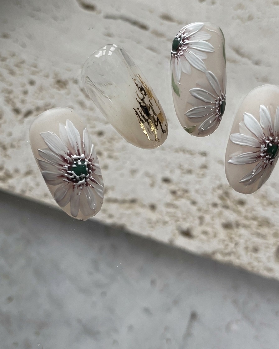Nahaufnahme des Nagels, nachdem das vierte weiße Blütenblatt zum Gänseblümchen-Muster hinzugefügt wurde.