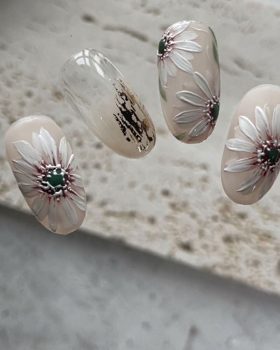 Nahaufnahme des Nagels, bei dem zusätzliche kürzere Blütenblätter in die Lücken des Gänseblümchens gemalt werden.