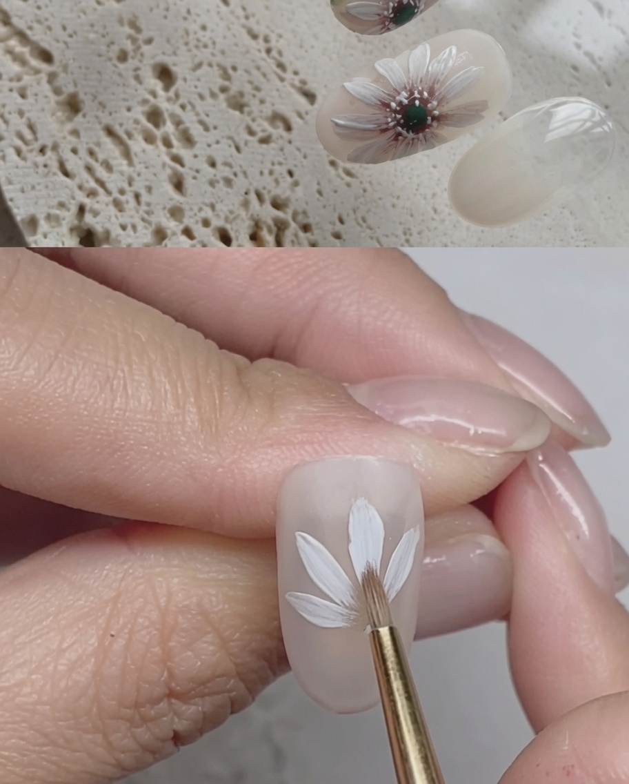 Nahaufnahme eines Nagels, der zeigt, wie weiße Gel-Pinselstriche eine zweite Schicht Blütenblätter über die erste legen.