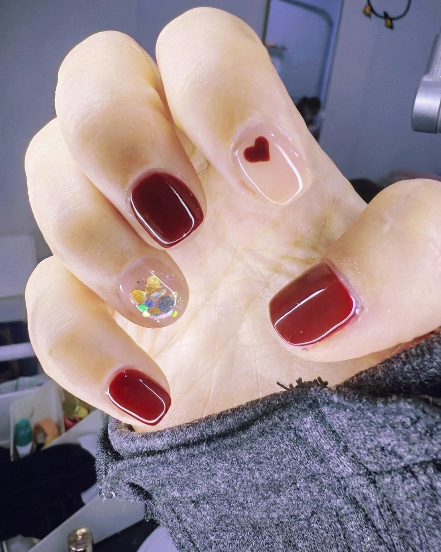 Ein Pinsel trägt eine klare Gelschicht auf den Akzentnagel auf, die für den Glitter feucht bleibt.