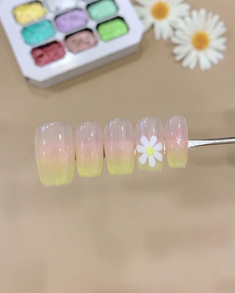Ein Schwamm tupft rosa und gelbes Gel auf eine Nagelspitze und erzeugt einen weichen Ombré-Verlauf.