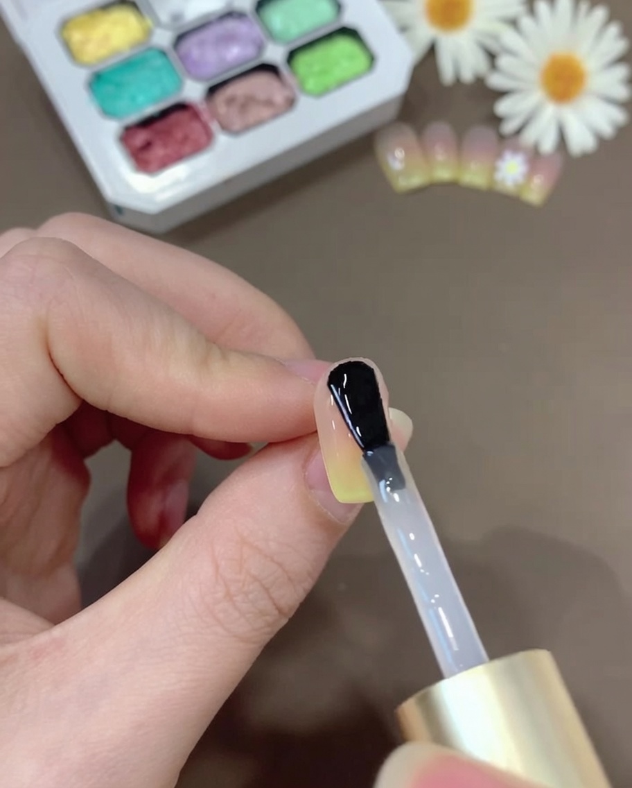 Ein Pinsel trägt klaren Top Gel auf den Ombré-Nagel auf, um für ein glänzendes Finish zu sorgen.