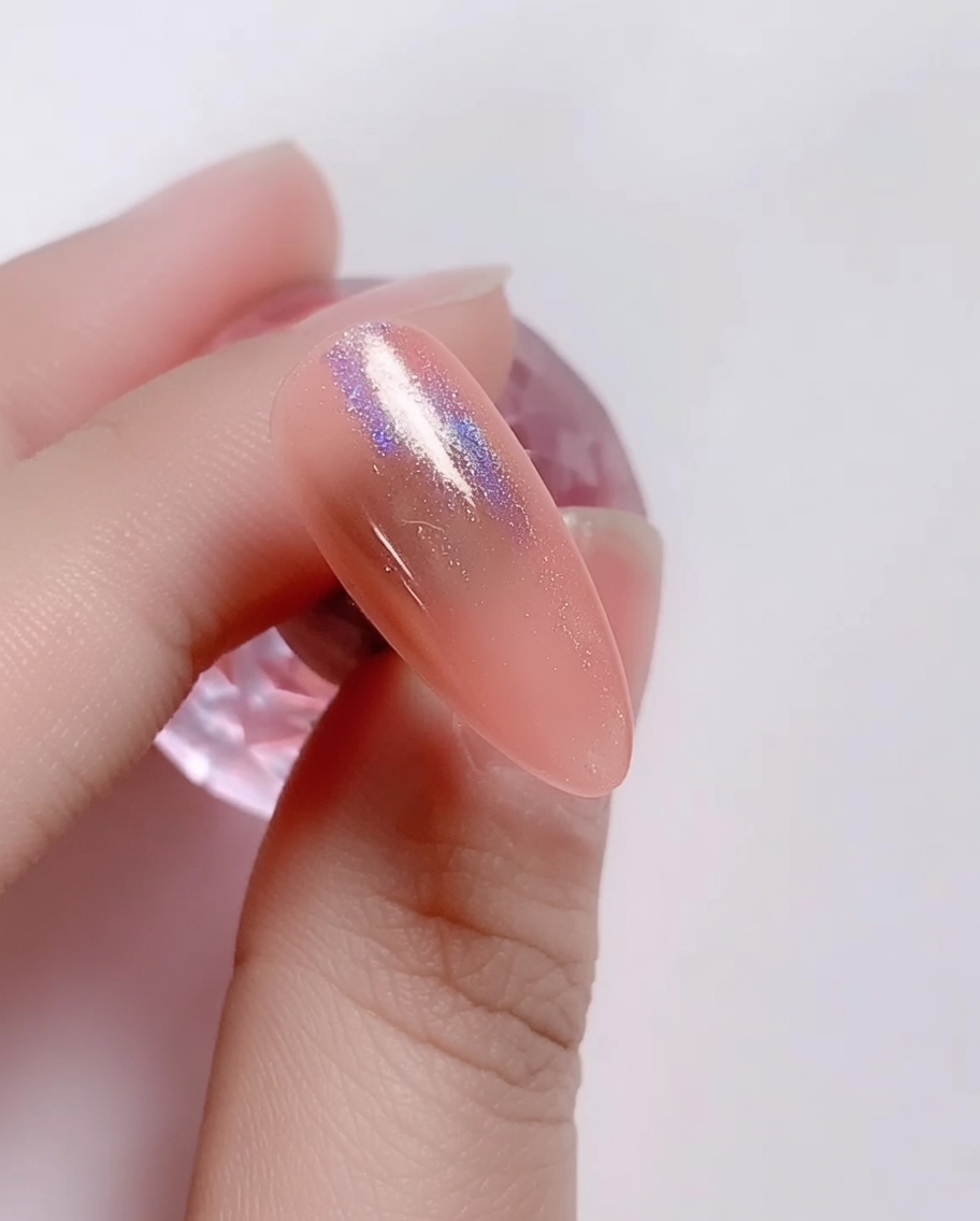 Ein Schwämmchen-Applikator reibt irisierendes Laserpuder in den rosa Gelnagel ein.