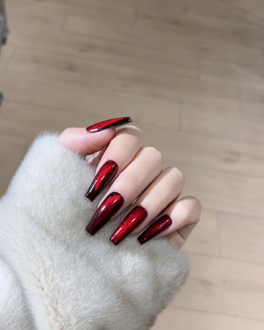 Eine Nahaufnahme eines Nagels, der mit einem schimmernden roten Magnet-Gel-Lack beschichtet wird.