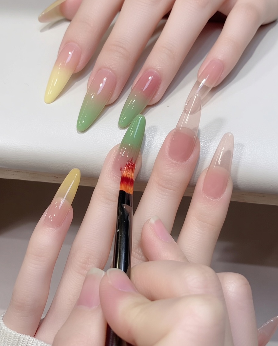 Nahaufnahme eines Ombré-Pinsels, der grünes Gel auf einem Nagel nach oben hin verblendet.