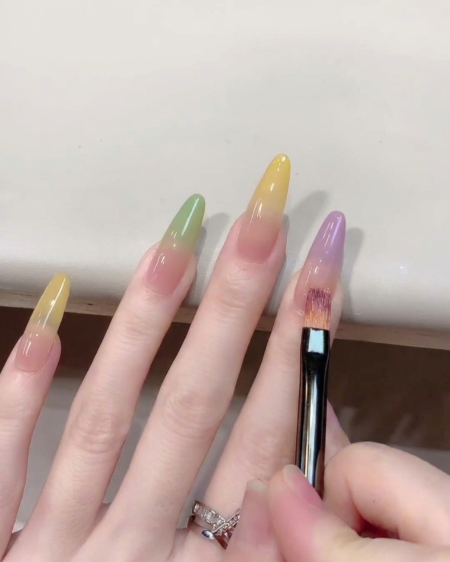 Nahaufnahme eines Ombré-Pinsels, der violettes Gel auf einem Nagel nach oben hin verblendet.