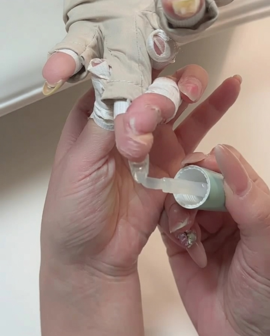 Eine Nahaufnahme eines Pinsels beim Auftragen von klarem Top Coat auf einen Fingernagel.