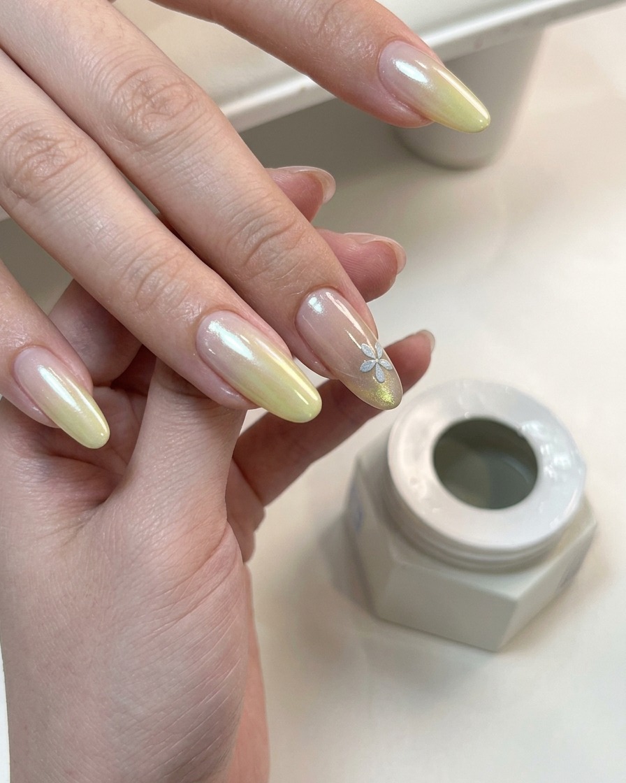 Eine Hand mit fertigem Farbverlauf und floralem Nageldesign härtet unter einer UV-Lampe aus.