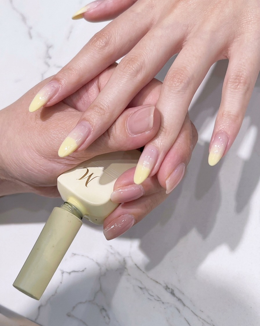 Nahaufnahme eines Pinsels, der die gelbe Spitzenfarbe nach unten in die Nagelmitte verblendet.