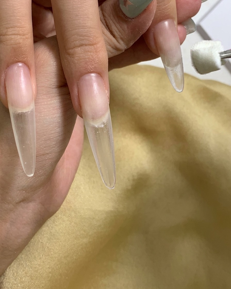 Nahaufnahme, wie ein Schwamm-Applikator Gel auf den Nagelhautbereich des Nagels aufträgt.