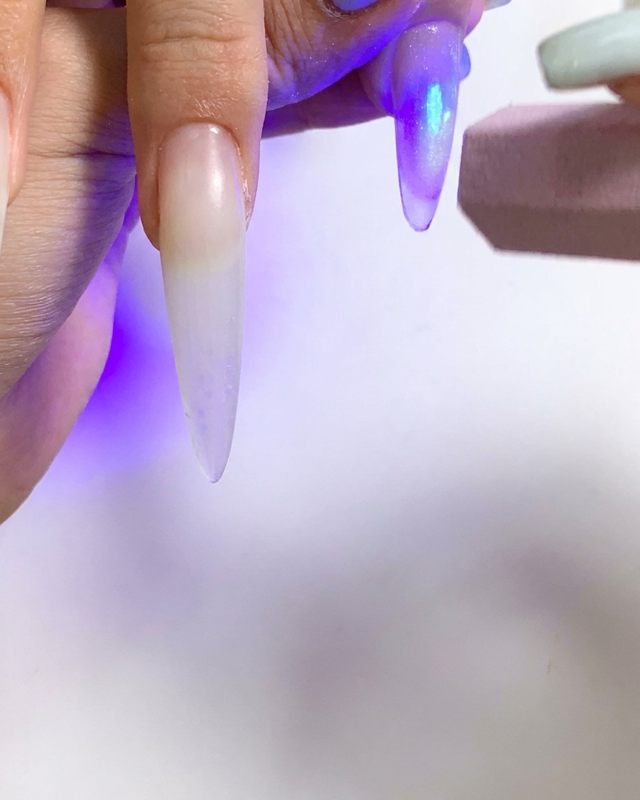 Eine kleine UV-Taschenlampe wird verwendet, um einen einzelnen Nagel mit Cat-Eye-Effekt zu härten.