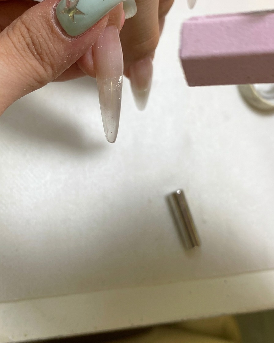 Eine kleine tragbare UV-Lampe härtet einen frisch magnetisierten Gelnagel.