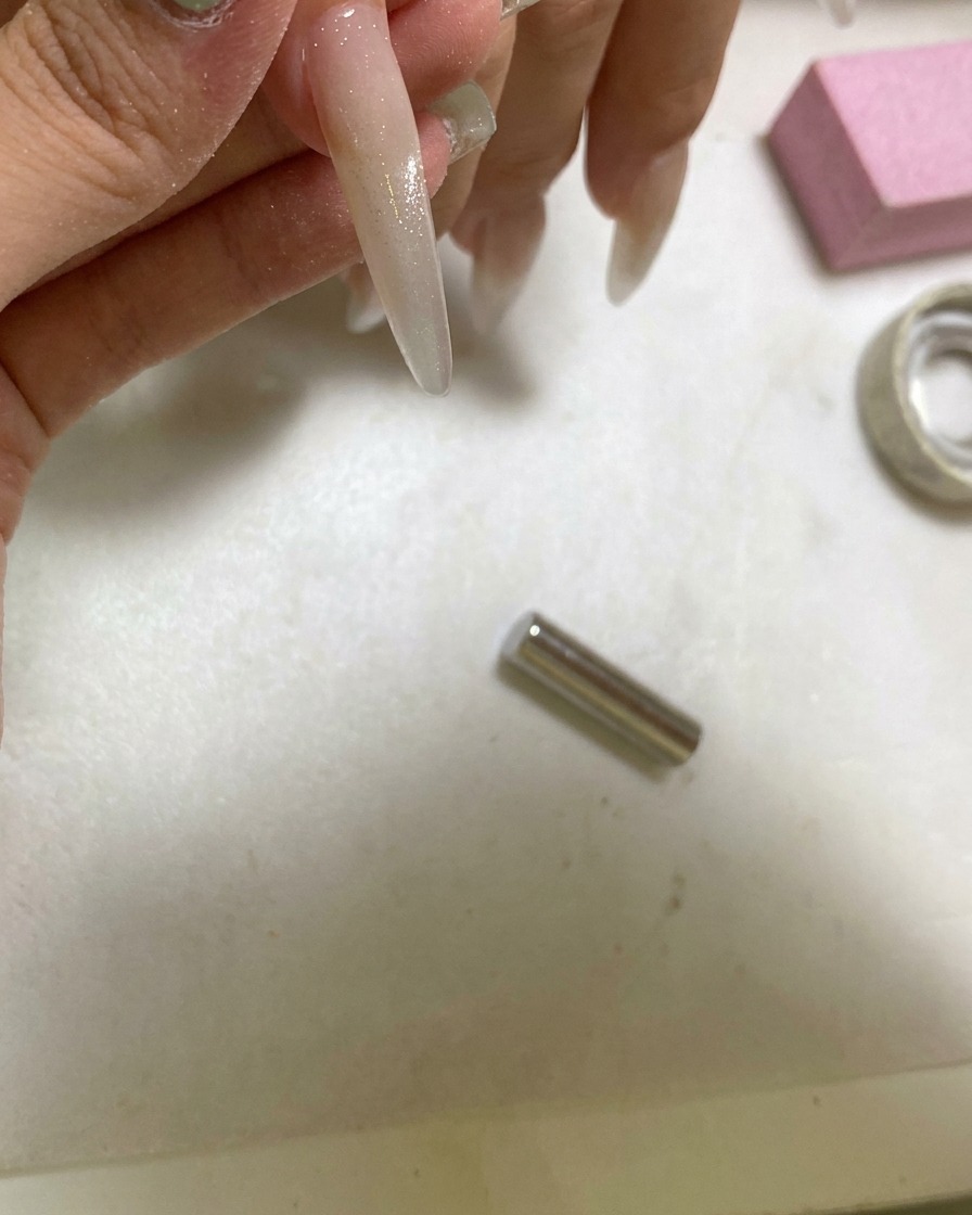 Eine tragbare UV-Lampe härtet einen Nagel, der mit einem Cat-Eye-Glaskugeleffekt gestylt wurde.