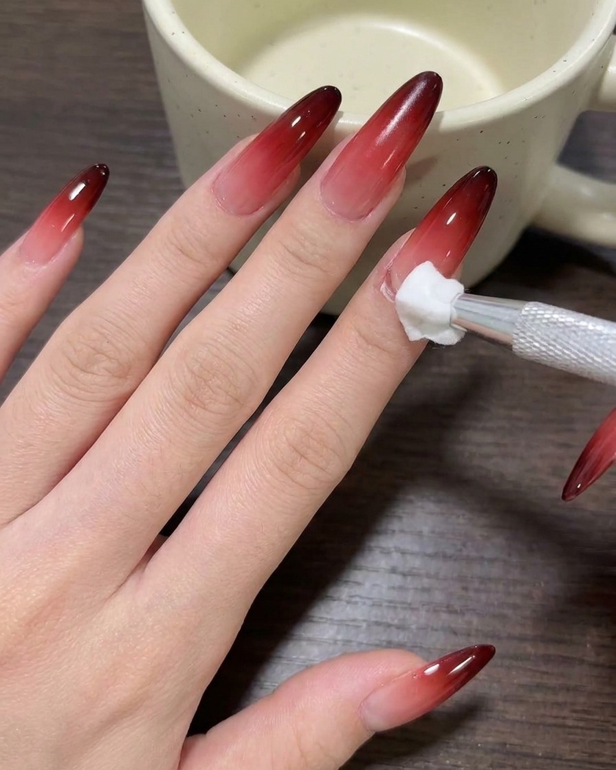 Eine Nahaufnahme eines Pinsels, der nudefarbenes Milchkaffee-Gel-Polish auf einen sauberen Nagel aufträgt.