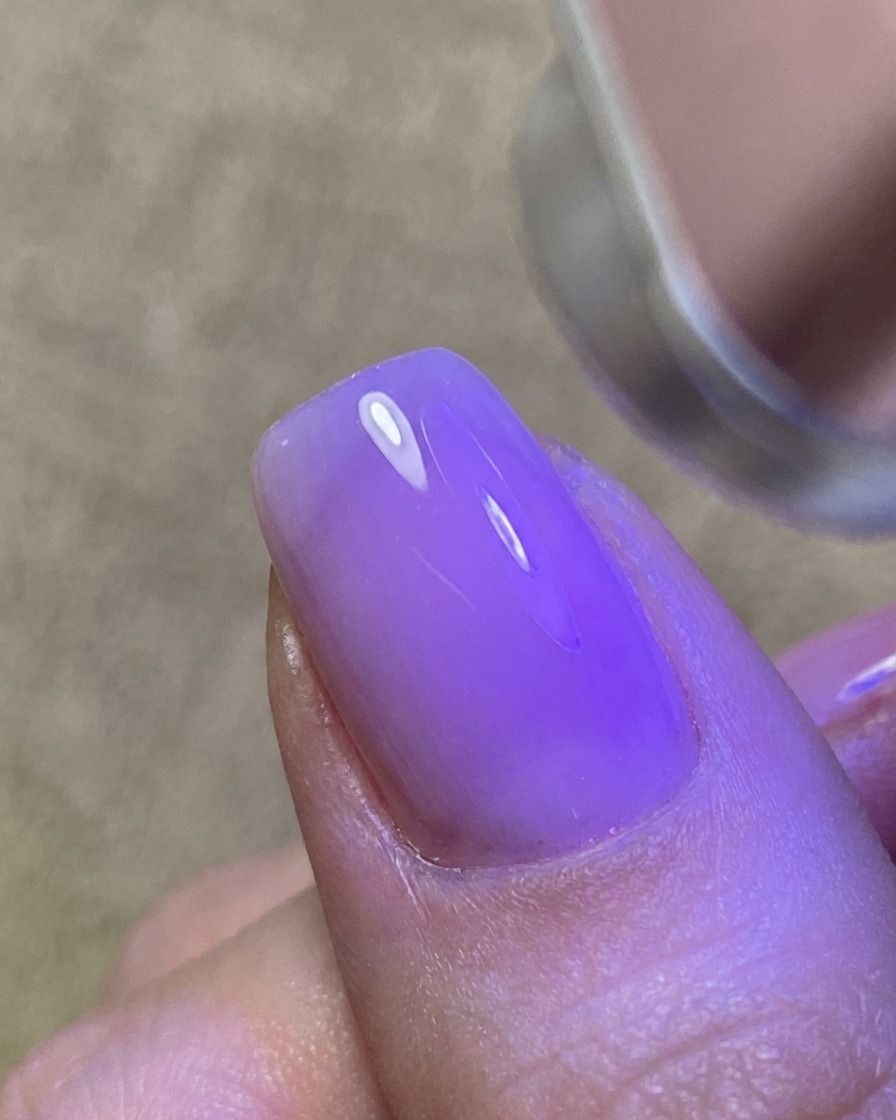 Eine dünne Schicht klares Gel wird auf den Nagel aufgetragen und erzeugt eine glänzende, klebrige Oberfläche.