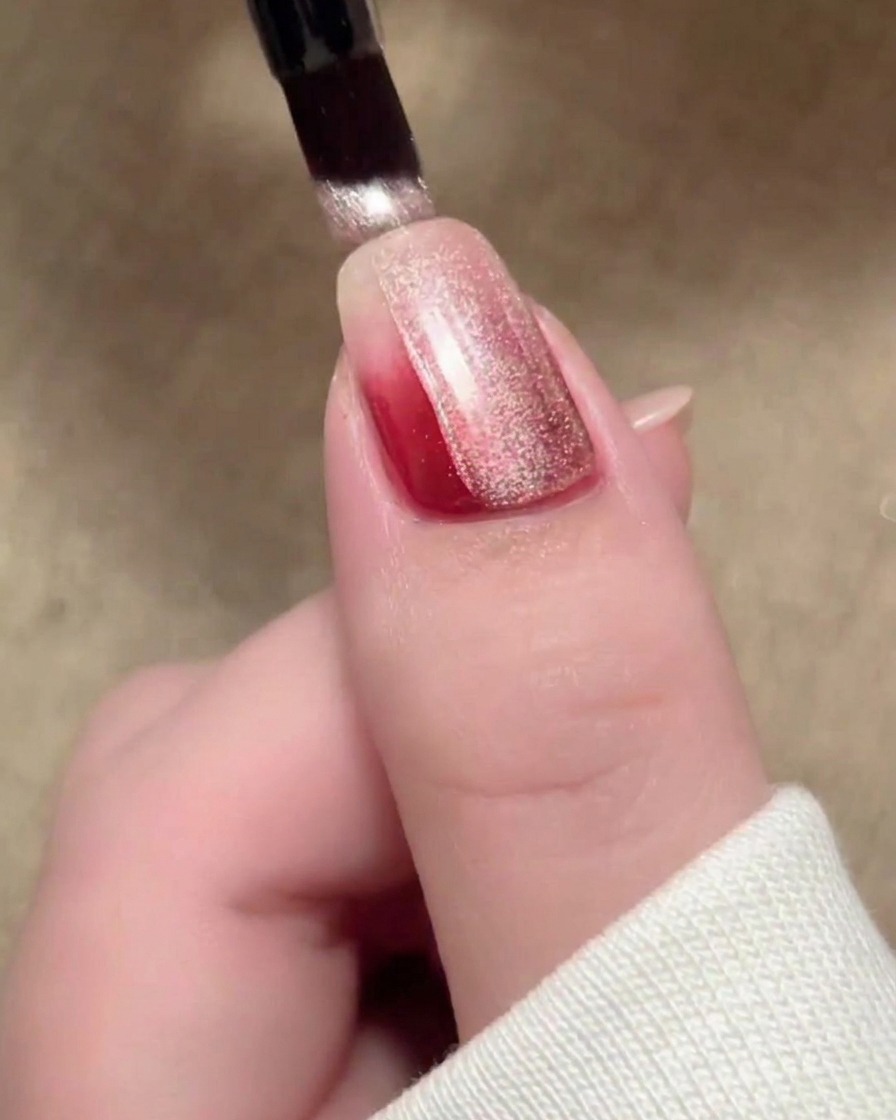 Ein Pinselstrich aus beigem magnetischem Cat-Eye-Lack bedeckt die Oberfläche des Nagels.