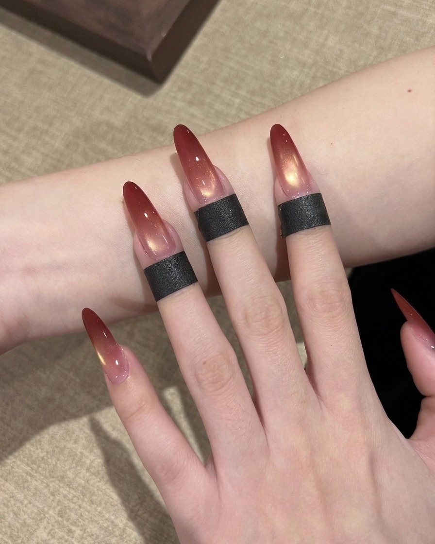 Eine Nahaufnahme eines Nagelpinsels, der rotes Gel-Polish auf die Spitze eines langen, mandelförmigen Kunstnagels tupft.