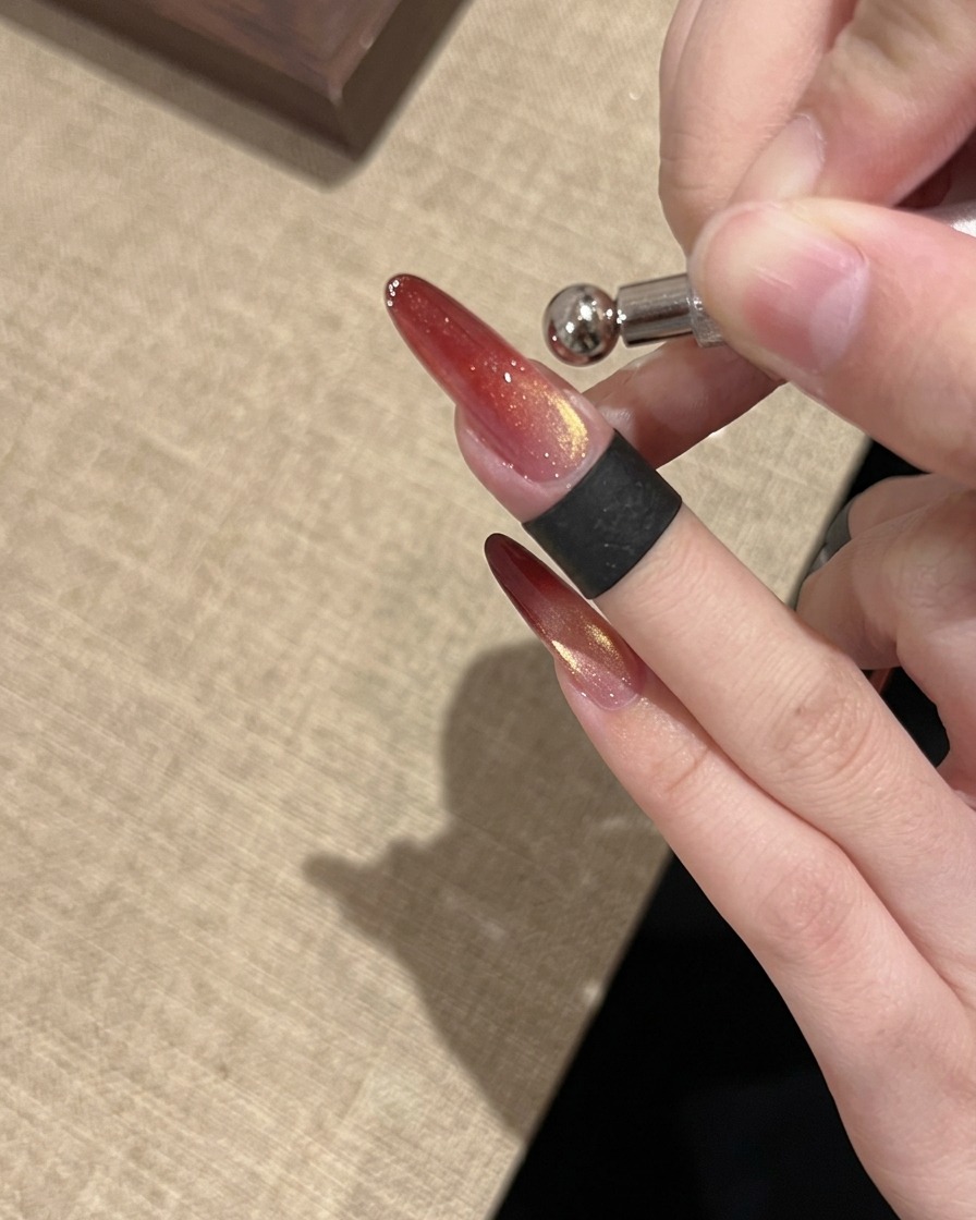 Ein Ringmagnet-Werkzeug, das verwendet wird, um eine helle, konzentrierte Glasperlen-Cat-Eye-Reflektion auf dem Nagel zu formen.