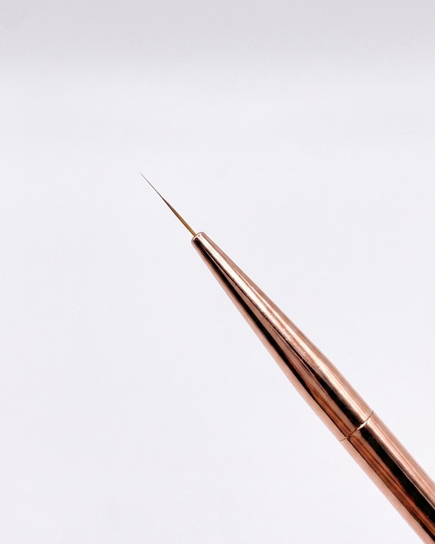 Eine Nahaufnahme eines feinen 12 mm Roségold-Liner-Pinsels mit spitz zulaufender Spitze vor neutralem Hintergrund.