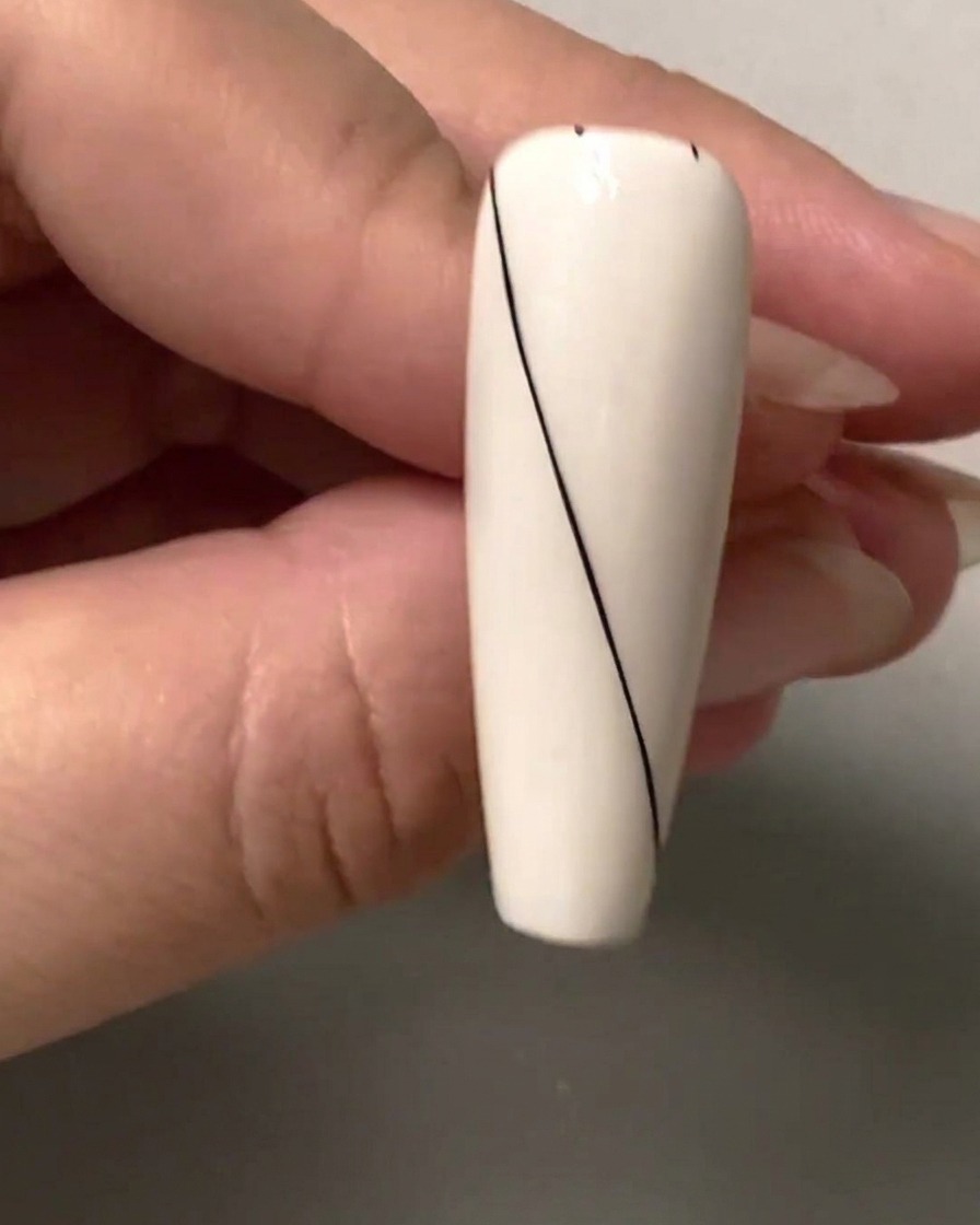 Eine Nahaufnahme eines Nagels mit kleinen schwarzen Abstandspunkten, die im oberen rechten leeren Bereich markiert sind.