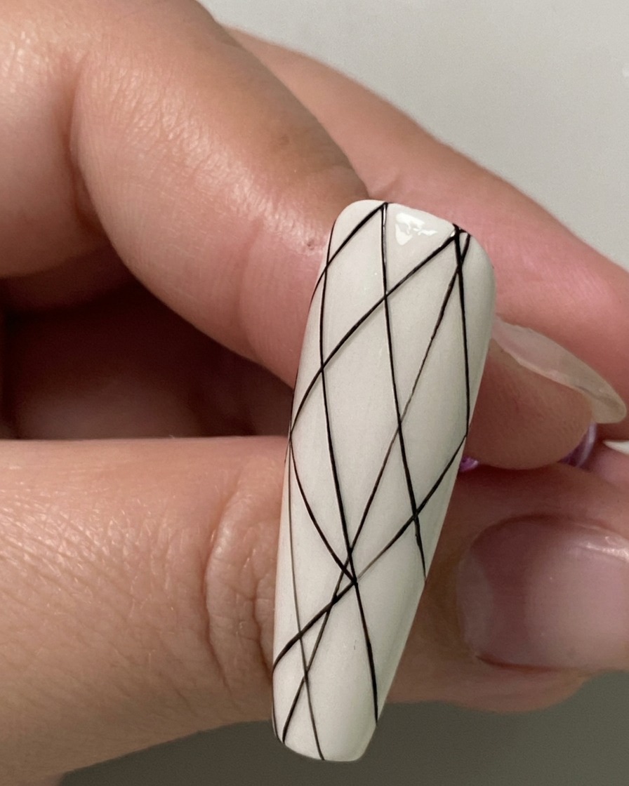Eine Nahaufnahme eines Nagels mit kleinen schwarzen Abstandspunkten, die entlang des unteren Bereichs markiert sind.
