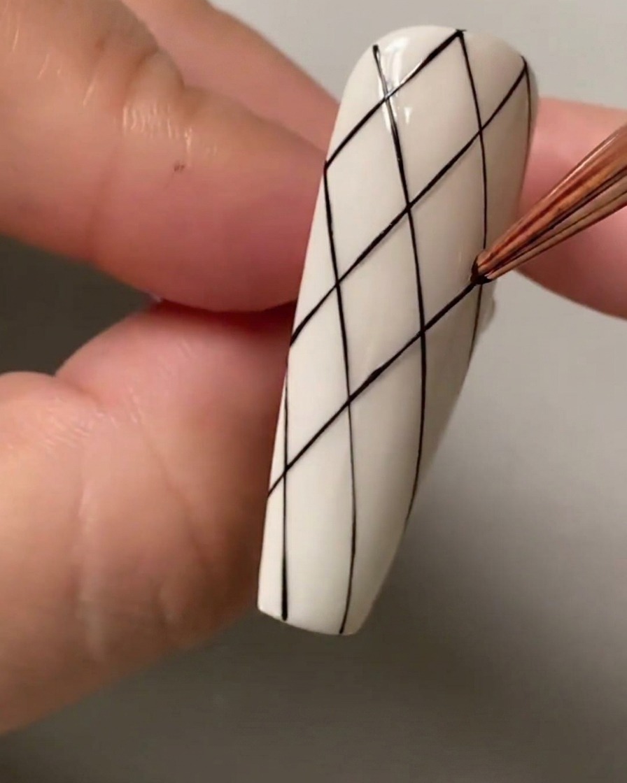 Nahaufnahme eines Liner-Pinsels, der Abstandspunkte im oberen Bereich des Nagels markiert.