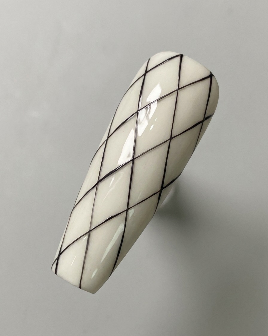 Ein vollständig gezeichnetes schwarzes Rauten-Gittermuster auf einer weißen Nagelbasis.