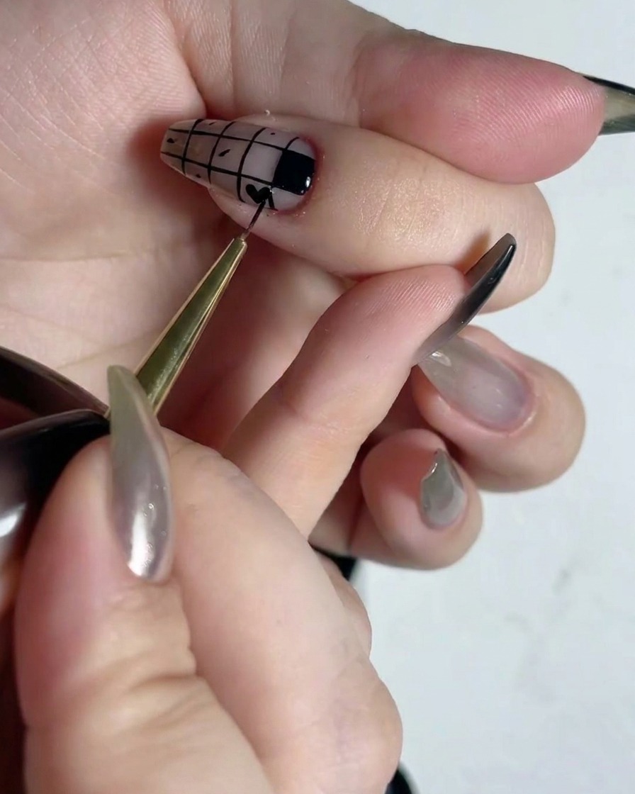 Ein feiner Detailpinsel füllt abwechselnde Quadrate eines Gittermusters auf einem Nagel mit schwarzem Lack aus.