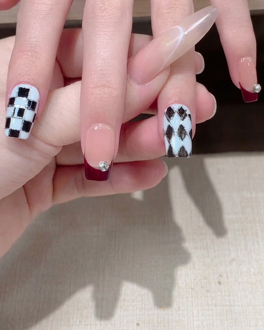 Nahaufnahme eines Fingers, bei dem ein geometrischer Linien-Sticker auf dem Nagel glattgestrichen wird.