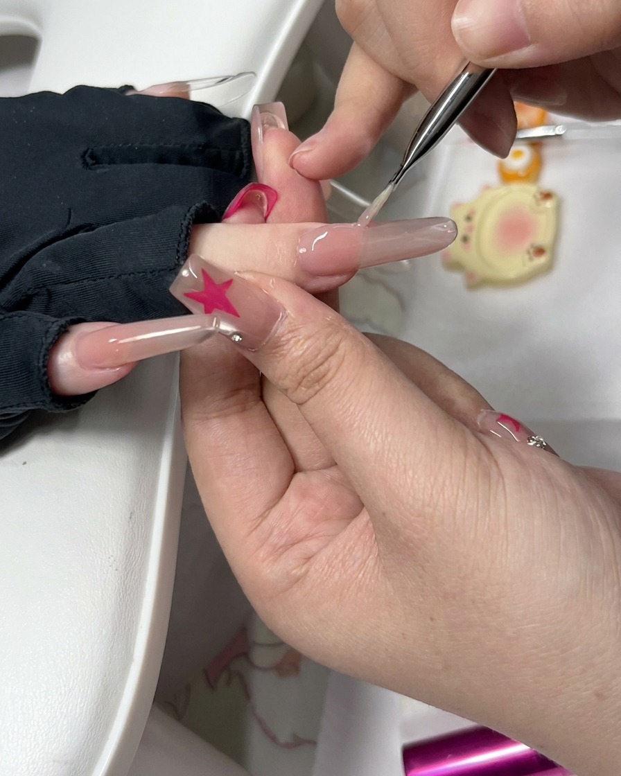 Eine Nahaufnahme eines Präzisionswerkzeugs und eines kleinen Schwamms, die den Rand eines vorbereiteten Fingernagels säubern.