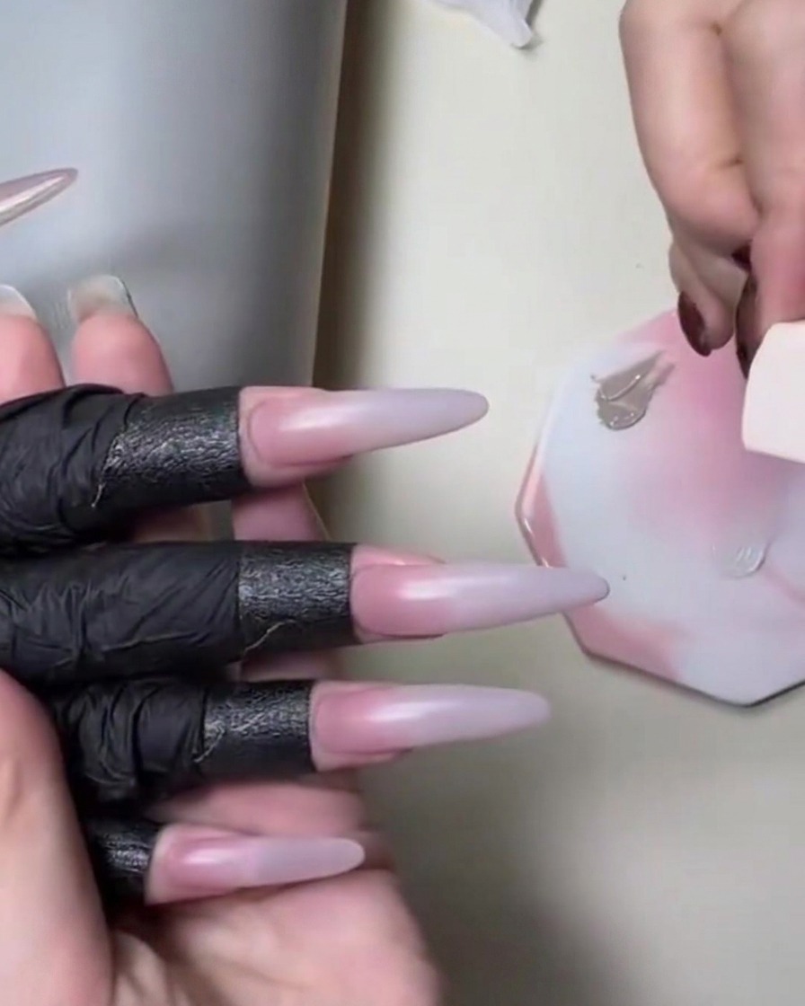 Ein Schwämmchen trägt hautfarbenes Nude-Gel neben einer weißen Farbpalette während eines Gradient-Nagel-Tutorials auf.