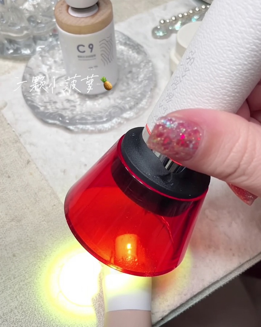 Eine tragbare rote Mini-UV-Lampe härtet einen Nagel an einem Finger aus.