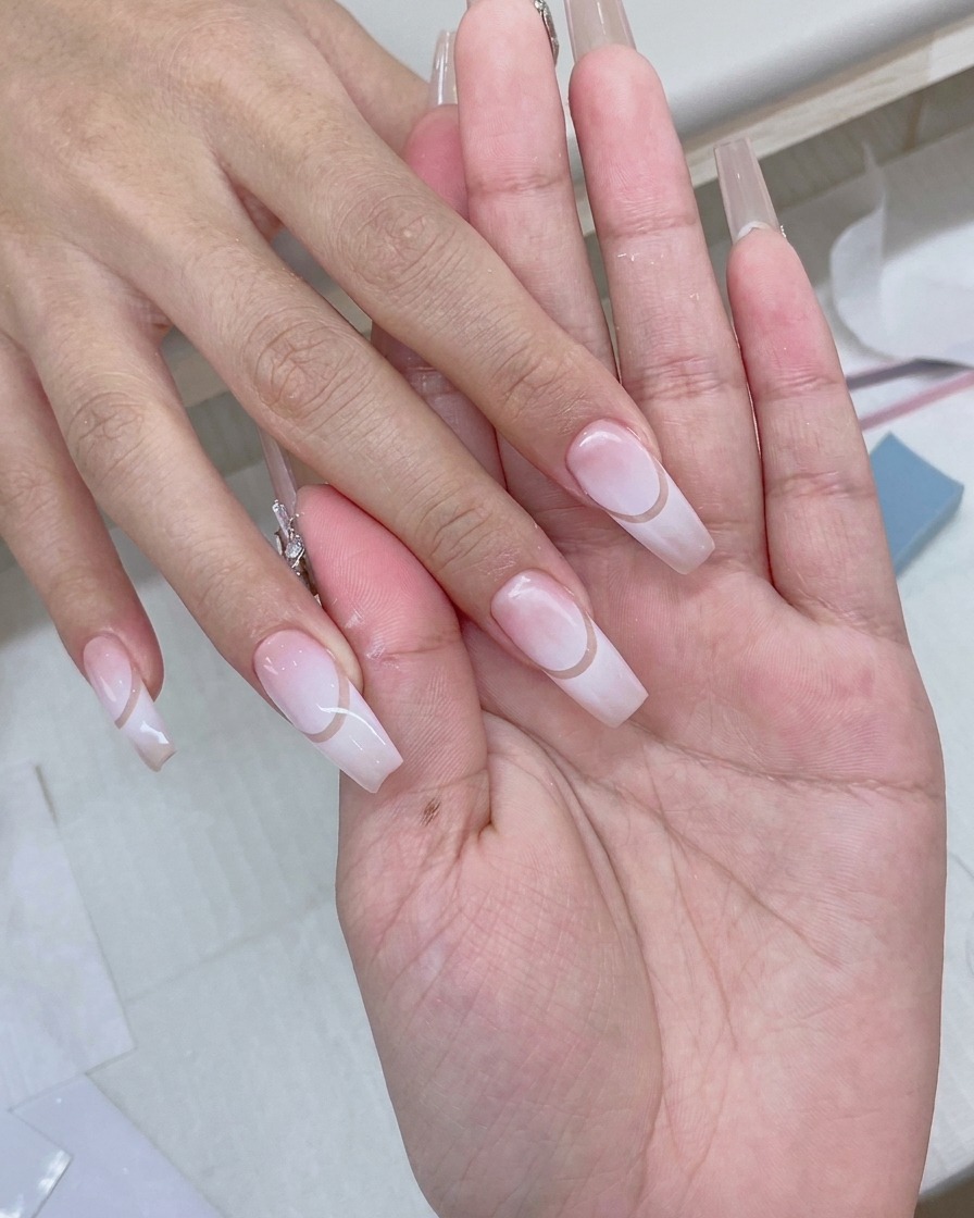 Ein Gelpinsel trägt einen klaren, glänzenden Top Coat über ein fertiges Gradient-Nageldesign auf.