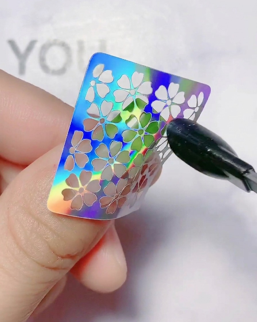 Ein hohler Blumen-Nagelsticker wird auf einen Nagel mit Farbverlauf gedrückt.