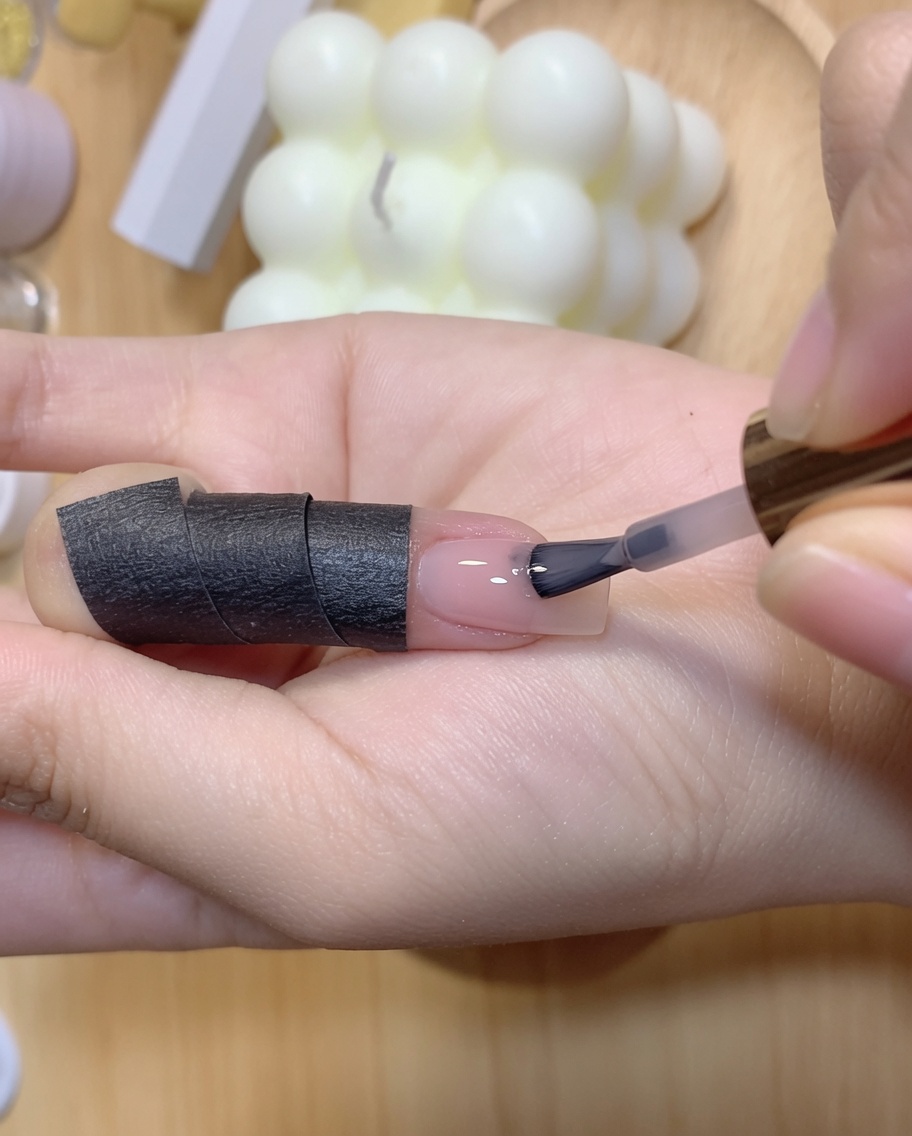 Eine Hand hält eine Härtungslampe über einen Fingernagel, der seine zweite Farbschicht erhält.