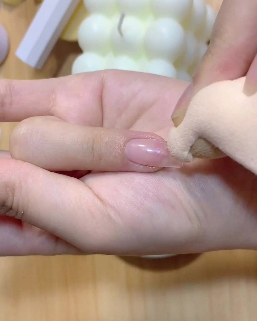 Ein Make-up-Schwamm tupft sanft Farbe auf einen Fingernagel, um einen Ombré-Farbverlauf zu erzeugen.