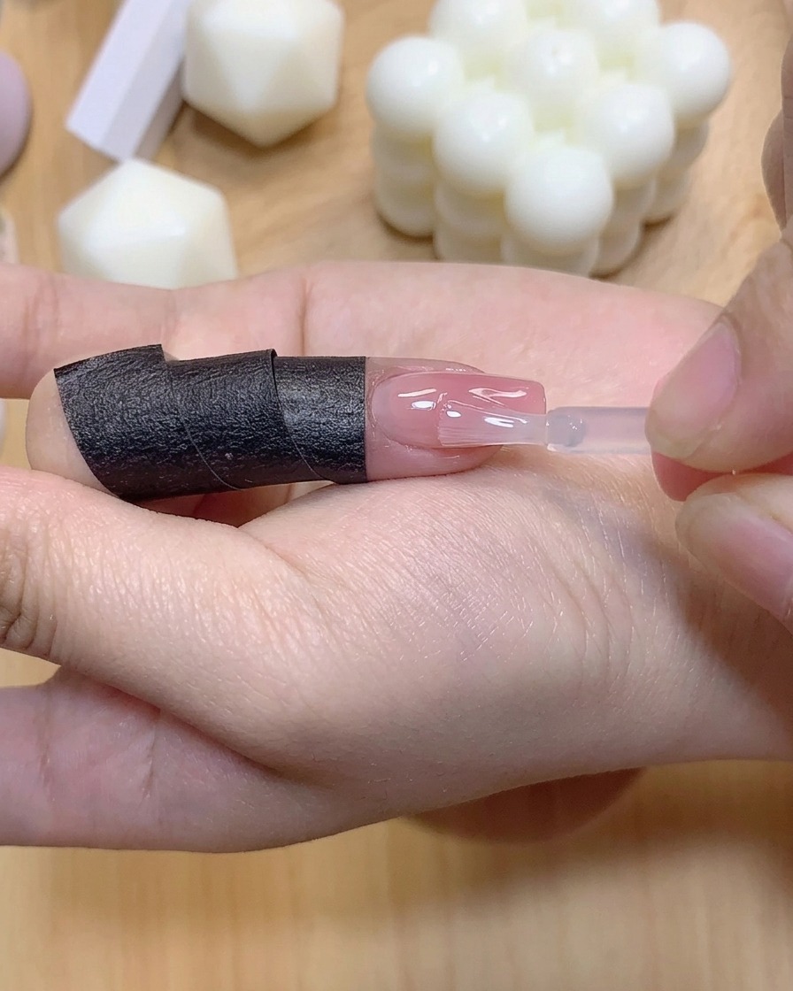 Ein kleiner Pinsel trägt eine klare Schicht Verstärkungsgel auf einen farbverlauften Fingernagel auf.