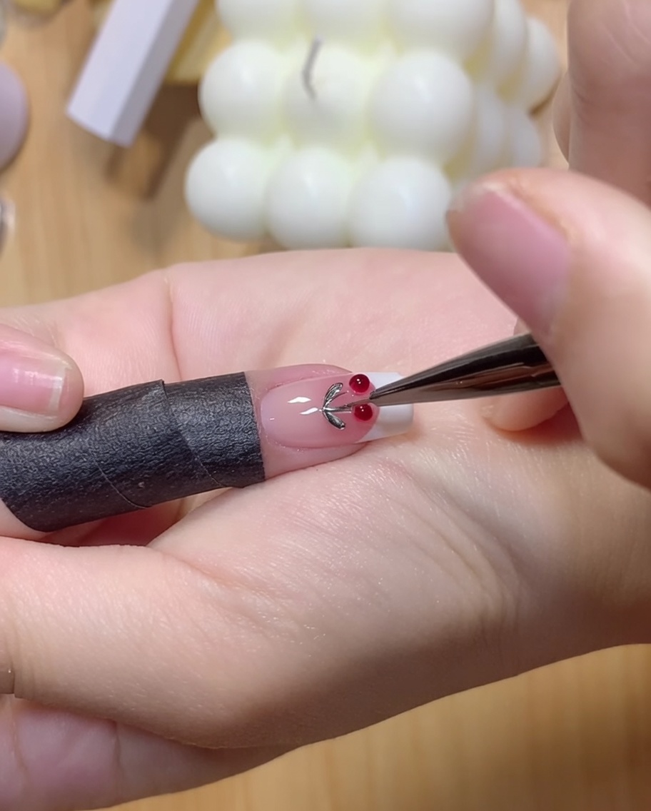 Ein Finger drückt leicht auf zwei klare Gelkugeln auf einer Nageloberfläche.