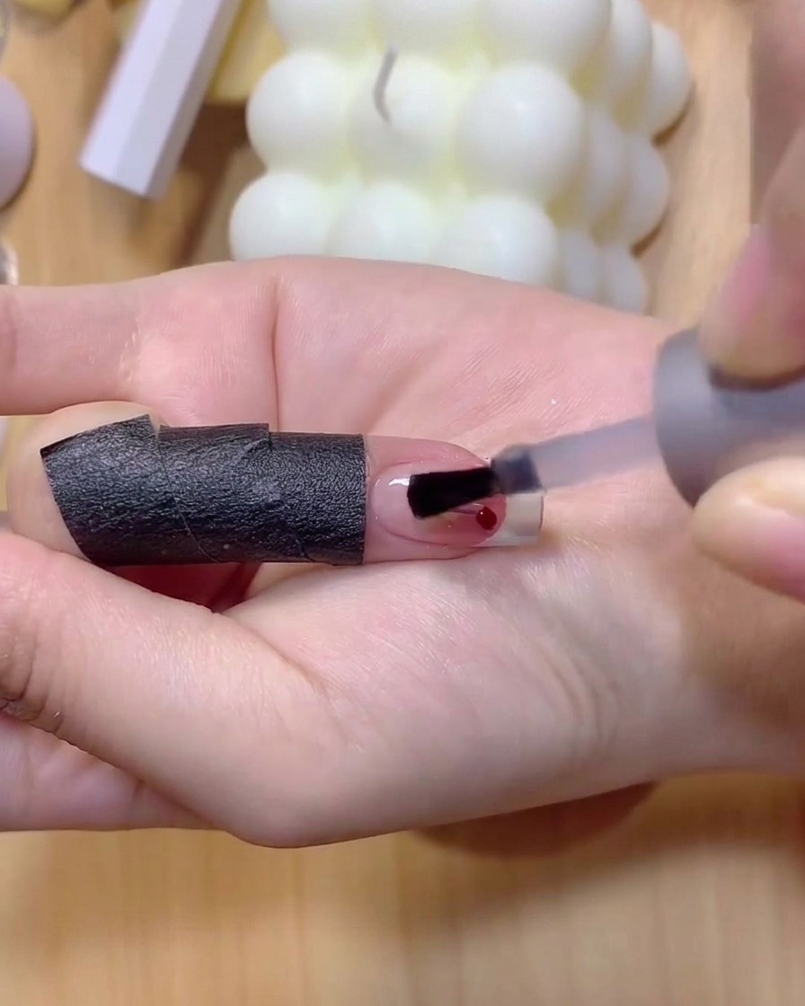 Ein feiner Nagelpinsel trägt hellbraunes Gel auf, um dünne Kirschstiele auf einen Nagel zu zeichnen.