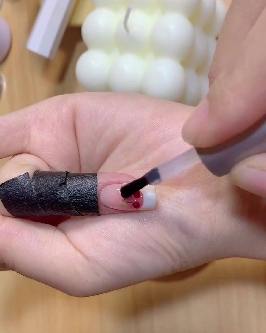Ein Pinsel trägt transluzentes rotes Gel über die klaren 3D-Kirschkugeln auf.