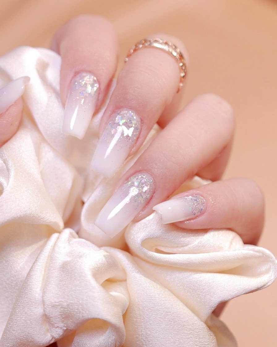 Ein feiner Nagelpinsel nimmt Silberglittergel aus einem kleinen schwarzen Behälter auf.