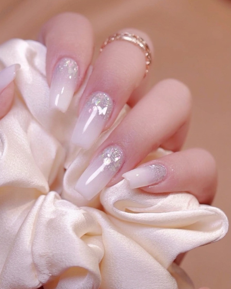 Ein elektrischer Nagelfräser feilt und glättet die Oberfläche eines manikürten Nagels.