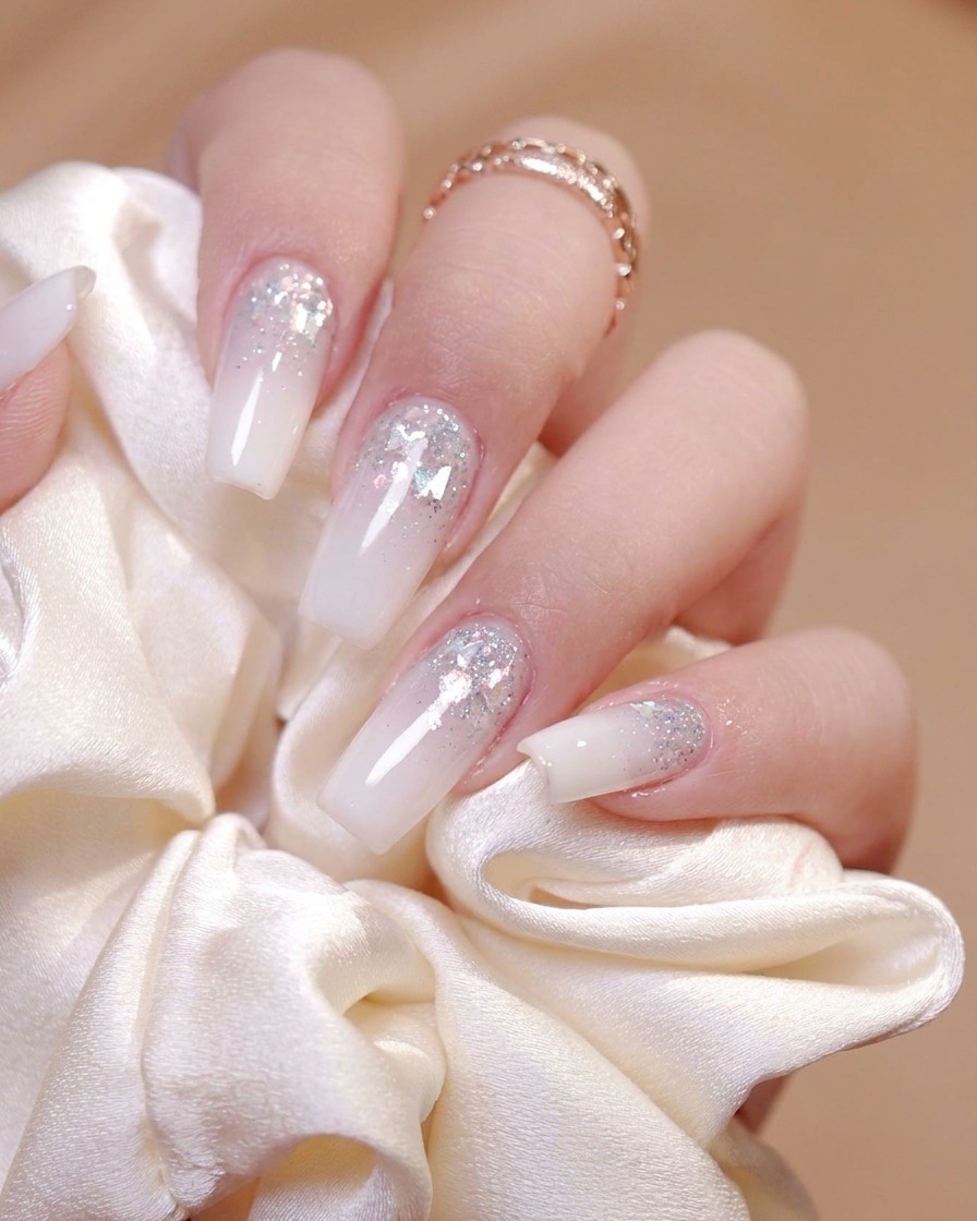 Ein Pinsel trägt einen glänzenden Top Coat gleichmäßig auf die Oberfläche eines dekorierten Nagels auf.