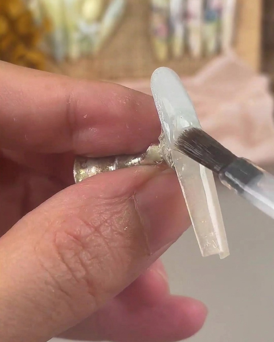 Ein Nagelpinsel überzieht den fertiggestellten Ombré-Nagel mit einer Schicht klarem Base Gel.
