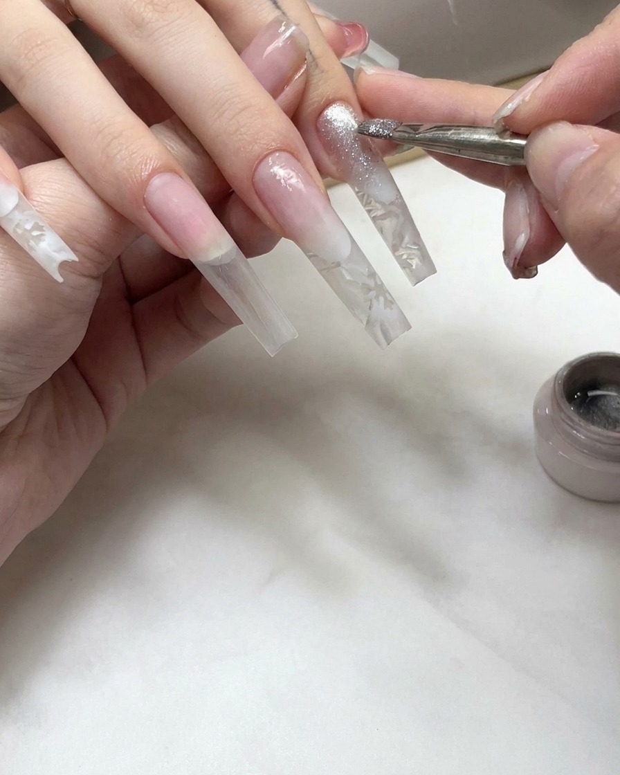 Ein Nagelpinsel trägt eine schimmernde Cat-Eye-Gelschicht auf den Spitzenbereich eines verlängerten Nagels auf.